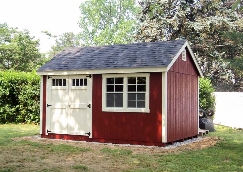 Red Cap Cod shed with white trim on foundation.