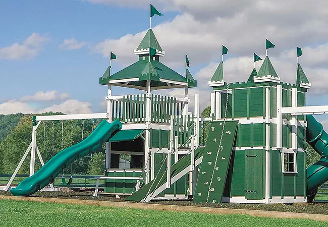 A large green play-set, with many different options for playing, at a park.